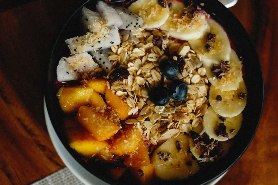 Tigela de açaí com aveia, granola e frutas da estação