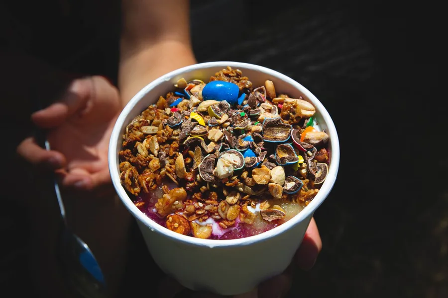 Açaí com confeitos de chocolate e granola em tigela branca