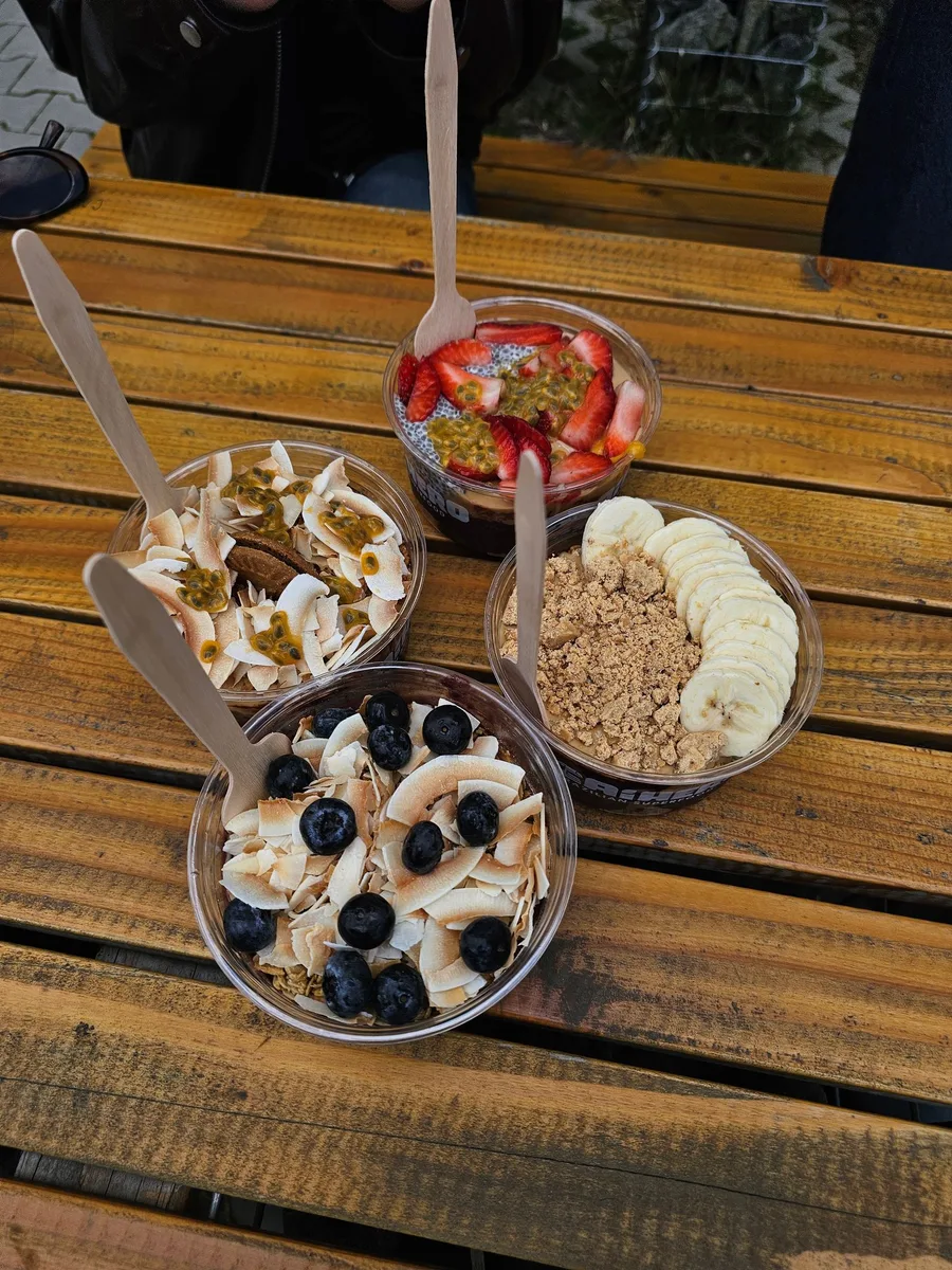 Quatro tigelas de açaí com coberturas diferentes na mesa de madeira